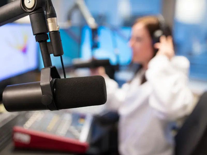A presenter speaking into a studio microphone in a radio station